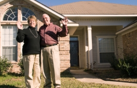 couple standing in frontyard waving
